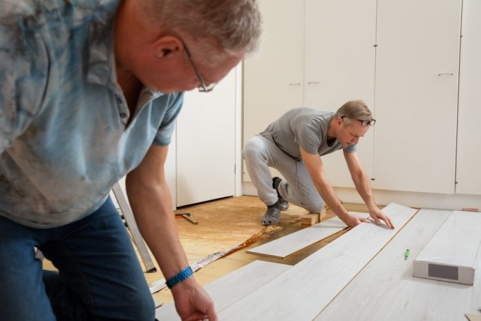 Laminate Flooring in Ottawa. Two mature men installing laminate flooring in a new home together. DIY concept. Professional renovation of a house.
