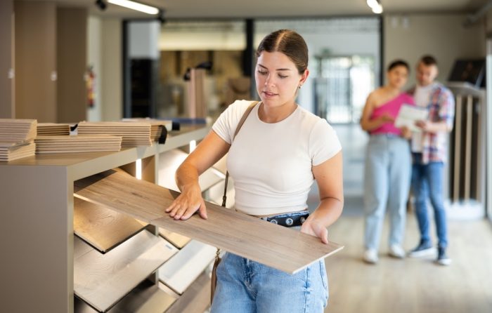 Laminate Flooring in Ottawa. Young woman buyer chooses sample of laminate flooring in hardware store.
