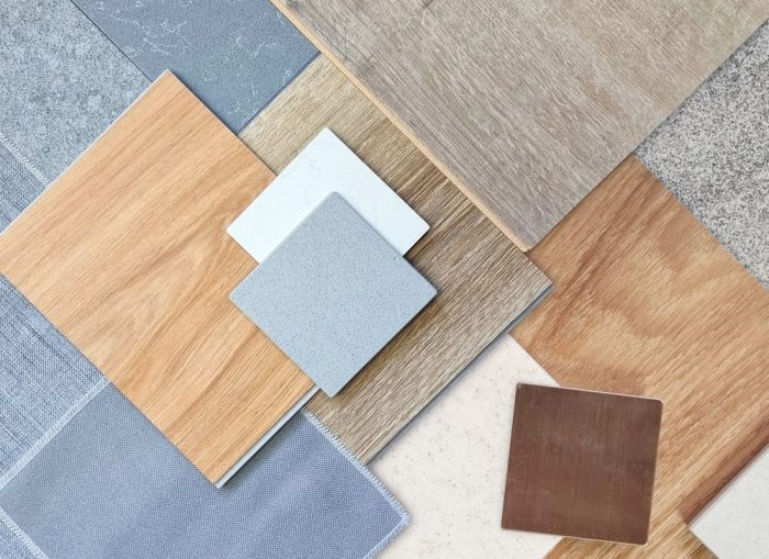 Flooring Solutions. top view of interior material samples contains wooden laminate flooring tile, artificial stone, wooden vinyl flooring tile, quartz stone, grey fabric, gold brushed stainless, stone tile in top view.