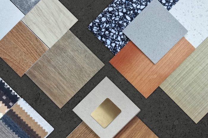 Flooring Solutions for Every Home. palette of interior material samples in top view contains wooden tiles, artificial stone, terrazzo, gold stainless, drapery, laminated placed on black marble stone table.