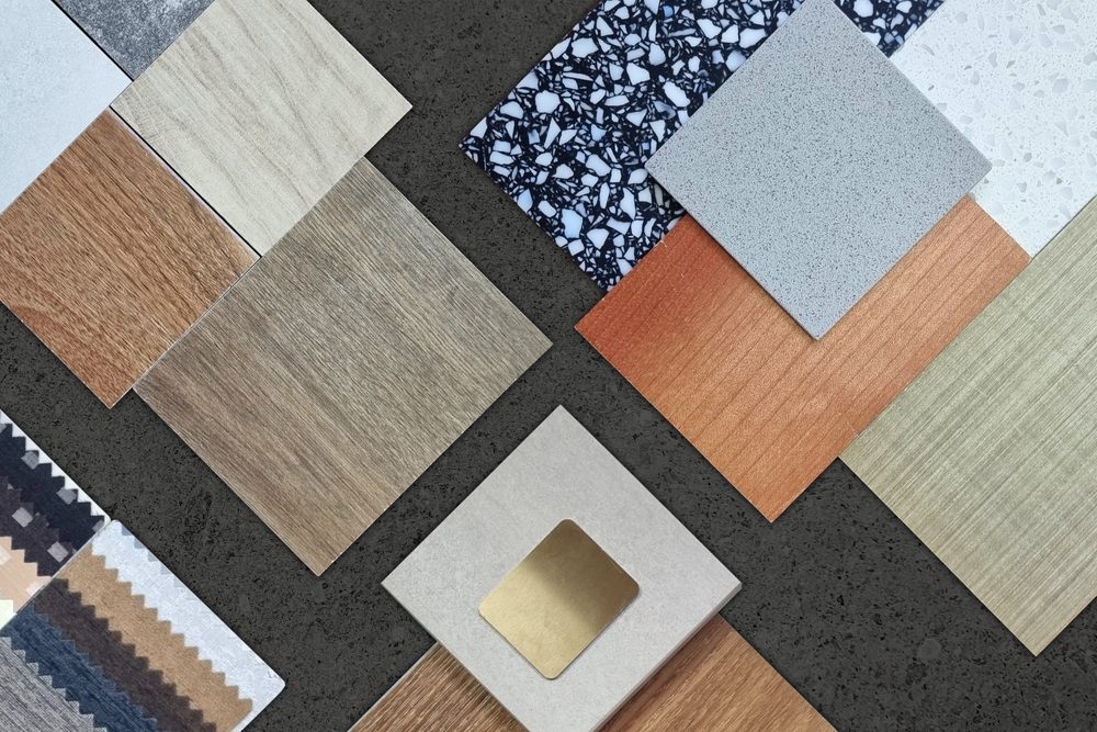 Flooring Solutions for Every Home. palette of interior material samples in top view contains wooden tiles, artificial stone, terrazzo, gold stainless, drapery, laminated placed on black marble stone table.