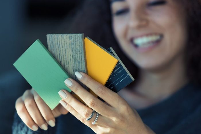 Why Visit Ottawa Diamond Flooring for Your Flooring Needs? An ethnically diverse, beautiful woman with perfect teeth is seen on her couch, engrossed in selecting colors from a wood sample palette for her home. Her enjoyment in personalizing her lifestyle.