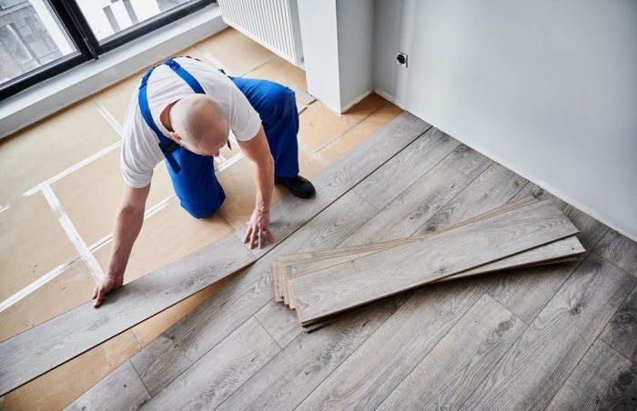 Why Visit Ottawa Diamond Flooring for Your Flooring Needs? Top view of male construction worker laying laminate wooden planks on floor underlayment. Man in work overalls installing laminate timber flooring in new flat. Home renovation concept.
