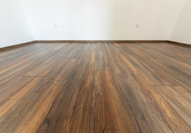 Why Visit Ottawa Diamond Flooring for Your Flooring Needs? Laminated wood floor with white wall. Empty room with floating laminate in new apartment.